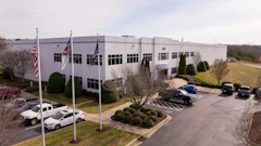 Corporate office building with flags, landscaped parking area and parked vehicles