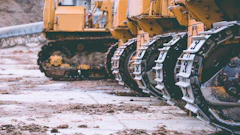 Yellow construction bulldozers with metal tracked wheels on muddy construction site