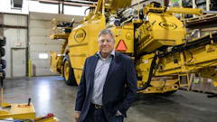 Executive standing in front of large yellow Weller industrial machinery in warehouse