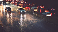Heavy traffic on wet highway at night with vehicle headlights and taillights reflecting on rain-soaked pavement
