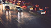 Heavy traffic on wet highway at night with vehicle headlights and taillights reflecting on rain-soaked pavement