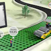 Dynapac roller compactor on green terrain with thermal imaging data displayed on tablet showing 94.3% density and 250°F temperature reading