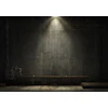 Silhouetted figure in dimly lit concrete industrial space with dramatic overhead lighting