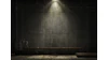 Silhouetted figure in dimly lit concrete industrial space with dramatic overhead lighting