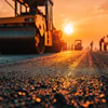Road roller compacting asphalt on construction site at golden sunset with workers in background