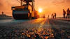 Road roller compacting asphalt on construction site at golden sunset with workers in background