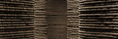 Stacked wooden logs arranged in organized rows at a timber storage facility