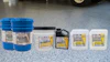 AmeriPolish concrete floor care products displayed in blue buckets and white containers on polished garage flooring