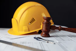 Yellow hard hat, wooden gavel, and construction blueprints arranged on white surface symbolizing construction law and safety compliance