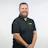 Professional man with beard wearing black DeWALT polo shirt, smiling at camera against white background Headshot