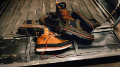 Orange and black work boots with safety gear arranged in a truck bed