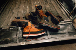 Orange and black work boots with safety gear arranged in a truck bed