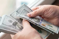 Hands holding a stack of US $100 bills fanned out