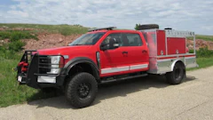 Red and silver fire truck with emergency equipment parked on rural road