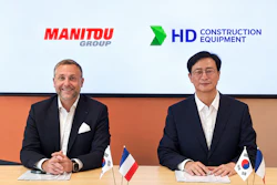 Two business executives at a formal meeting with Manitou Group and HD Construction Equipment logos, French and South Korean flags on table