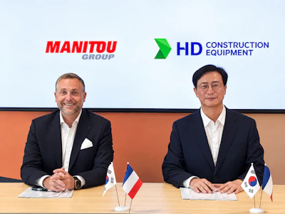 Two business executives at a formal meeting with Manitou Group and HD Construction Equipment logos, French and South Korean flags on table