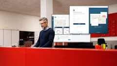 Professional man at red desk reviewing analytics dashboards and software interfaces on multiple computer monitors