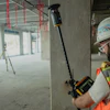 Construction worker using laser level tool on concrete wall at job site