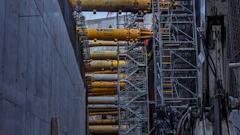 Industrial construction site with yellow hydraulic cylinders mounted on steel scaffolding and concrete walls