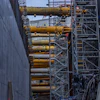Industrial construction site with yellow hydraulic cylinders mounted on steel scaffolding and concrete walls