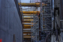 Industrial construction site with yellow hydraulic cylinders mounted on steel scaffolding and concrete walls
