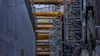 Industrial construction site with yellow hydraulic cylinders mounted on steel scaffolding and concrete walls