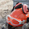 Orange safety hard hat with reflective stripes and protective goggles on a tire at a construction site