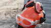 Orange safety hard hat with reflective stripes and protective goggles on a tire at a construction site