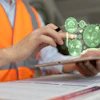 Construction worker in orange safety vest using tablet with green holographic sustainability and environmental monitoring icons