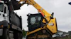 Yellow CAT skid steer loader loading gravel into white dump truck on construction site
