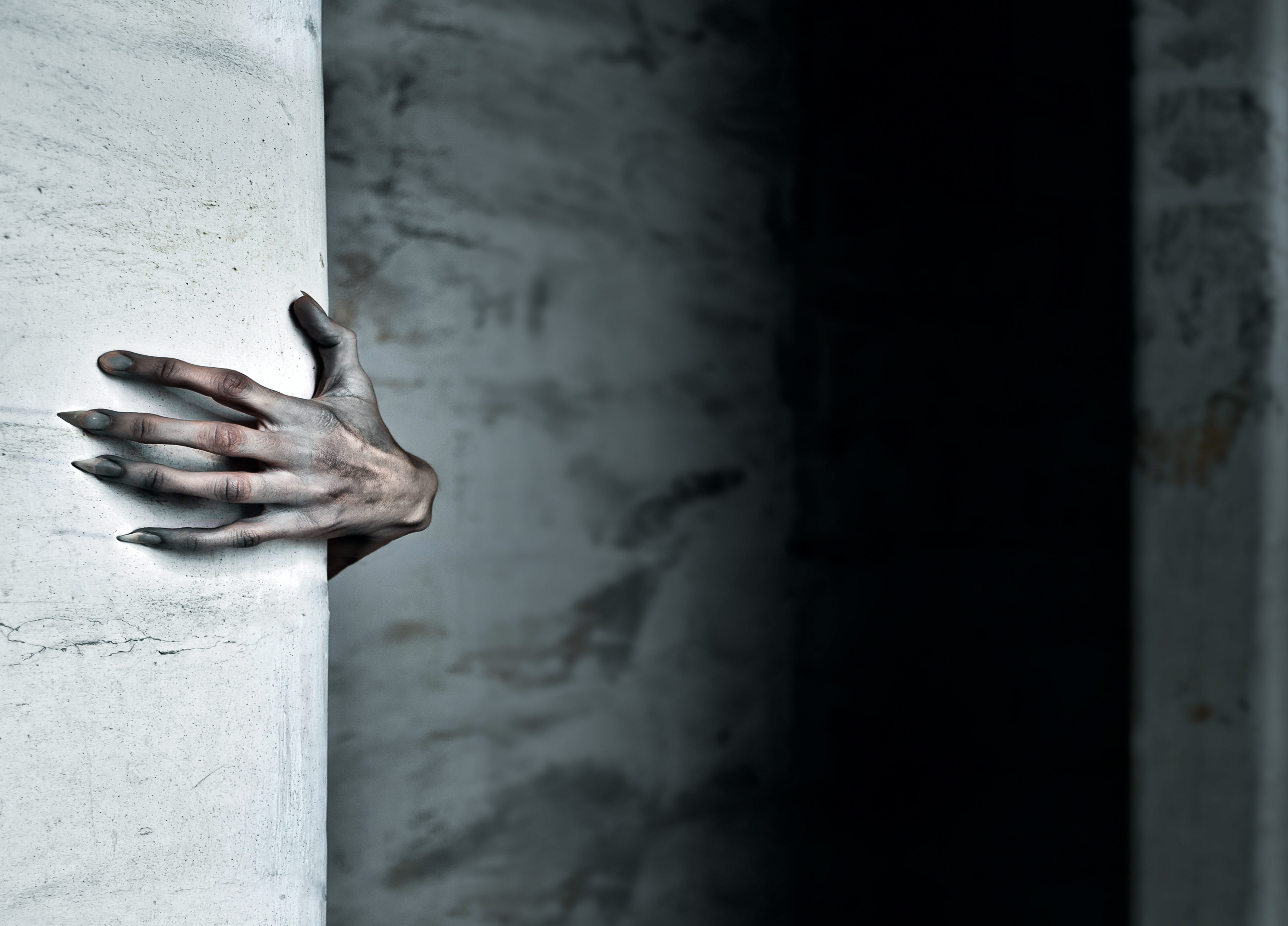 Sculptural hand emerging from white wall in dramatic lighting against dark background