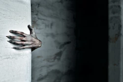 Sculptural hand emerging from white wall in dramatic lighting against dark background