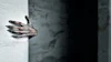 Sculptural hand emerging from white wall in dramatic lighting against dark background