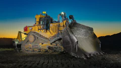 Caterpillar bulldozer with raised blade at sunset on construction site