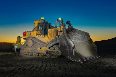 Caterpillar bulldozer with raised blade at sunset on construction site