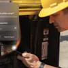 Construction worker in hard hat and safety vest inspecting hydraulic equipment during site inspection