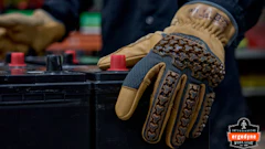 Close-up of tan and black tactical work gloves with textured grip pattern worn during hands-on task