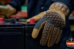 Close-up of tan and black tactical work gloves with textured grip pattern worn during hands-on task