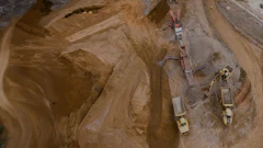 Aerial view of construction site with heavy machinery, excavators, and trucks on sandy terrain
