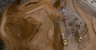 Aerial view of construction site with heavy machinery, excavators, and trucks on sandy terrain