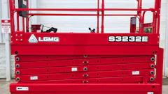 Red LGMG S3232E electric scissor lift with safety railings and control panel displayed against white garage door