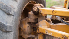 Close-up of rusted wheel hub and axle assembly on heavy construction equipment with yellow metal frame