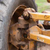 Close-up of rusted wheel hub and axle assembly on heavy construction equipment with yellow metal frame