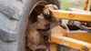 Close-up of rusted wheel hub and axle assembly on heavy construction equipment with yellow metal frame