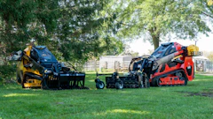 Yellow and red landscaping compactor equipment displayed on grass with trees in background