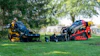 Yellow and red landscaping compactor equipment displayed on grass with trees in background