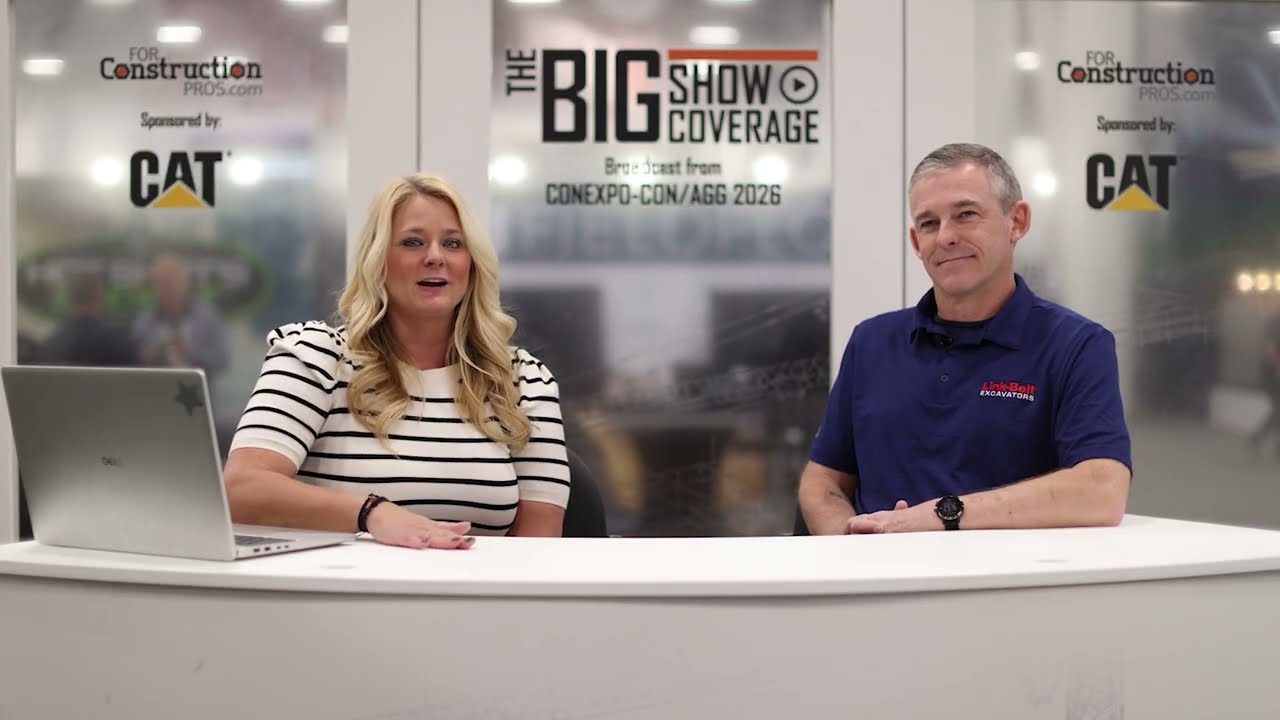 Two professionals at a broadcast desk during The Big Show Coverage event, with CAT sponsorship backdrop visible