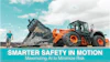 Orange wheel loader dumping gravel with worker and digital safety overlay on turquoise sky background