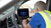 Construction worker in safety vest using Toughbook laptop in vehicle at job site
