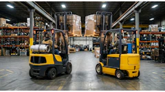Two yellow and black forklifts operating in an industrial warehouse with shelving and pallets